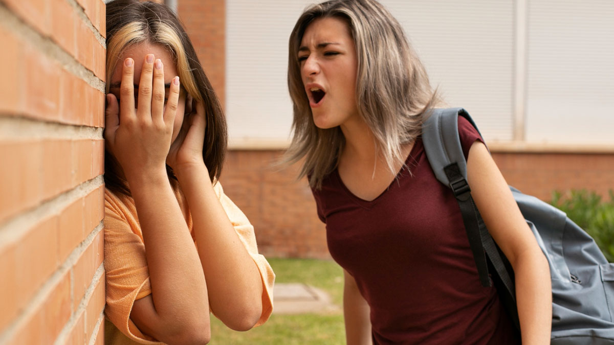 Teen girl aggressively confronting another student outside school, illustrating popular kids who became outcasts behavior.