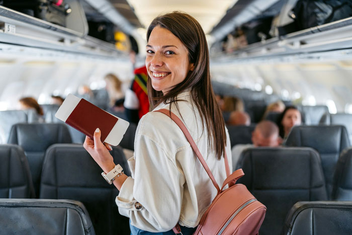 Young woman holding passport and boarding pass, smiling confidently on an airplane amid rude fam bullying seat swap. Young woman holding passport and boarding pass, smiling confidently on an airplane amid rude fam bullying seat swap.