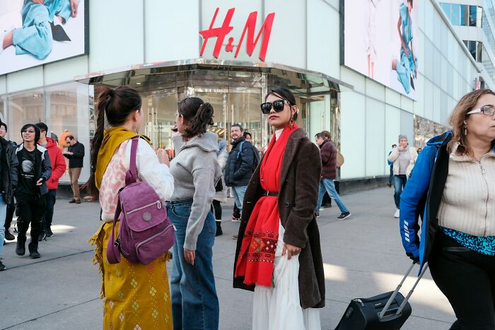 People standing outside an H&M store in busy street, illustrating long grudges and social interactions.