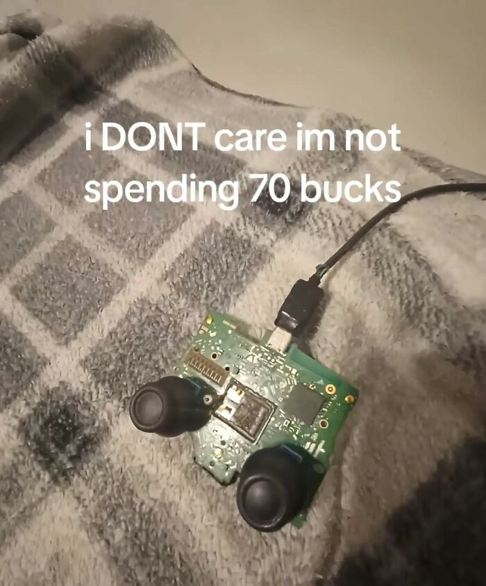 Exposed circuit board with joystick buttons and USB cable on patterned fabric, showcasing pleasures of the occult humor.