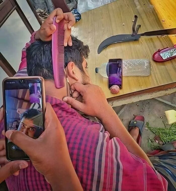 Man shaving with scissors using a phone screen as a mirror, showing an out of context moment from pleasures of the occult.