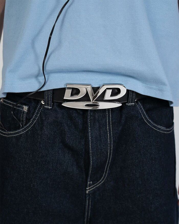 Close-up of a person wearing a DVD belt buckle on dark jeans and a light blue shirt, a humorous out of context occult item.