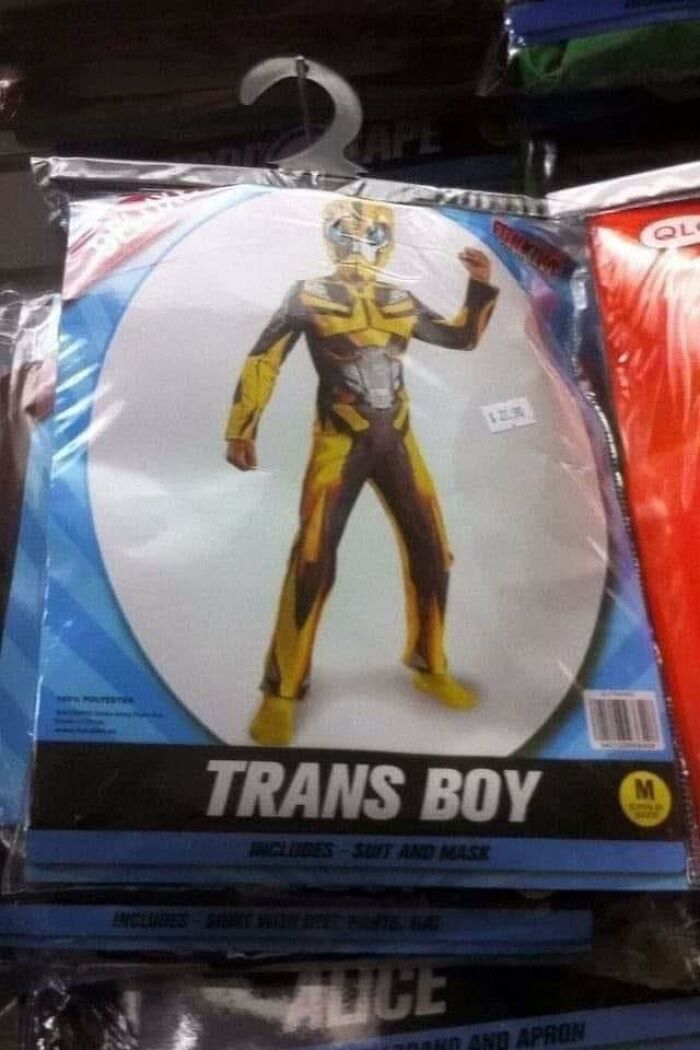 Child superhero costume labeled trans boy in packaging, displayed for sale with bright yellow and black design.
