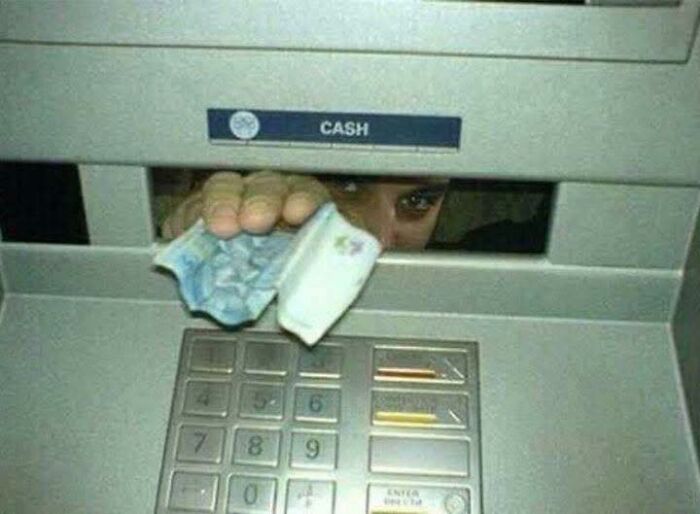 Person peeking through ATM cash slot holding crumpled bills, a humorous out of context moment related to pleasures of the occult.