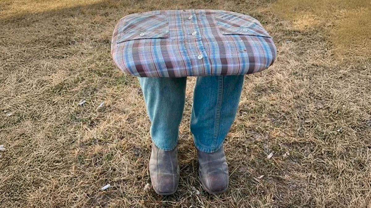 Plaid shirt stuffed and shaped like legs with jeans and boots standing on dry grass in a bizarre online selling example.