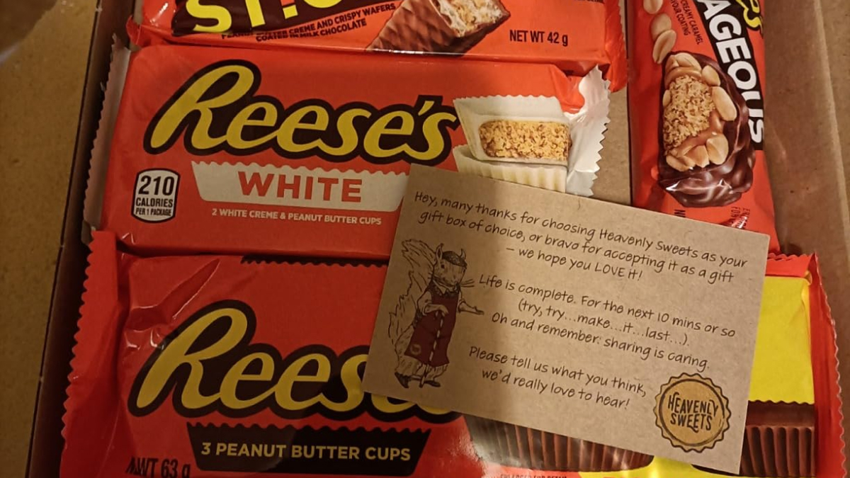 Assorted popular Halloween candy including Reeseu2019s peanut butter cups and other chocolate treats in a gift box.