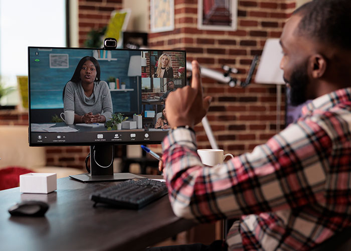 Man in plaid shirt engaging in a virtual meeting, contemplating exposing management and HR to coworkers. Man in plaid shirt engaging in a virtual meeting, contemplating exposing management and HR to coworkers.
