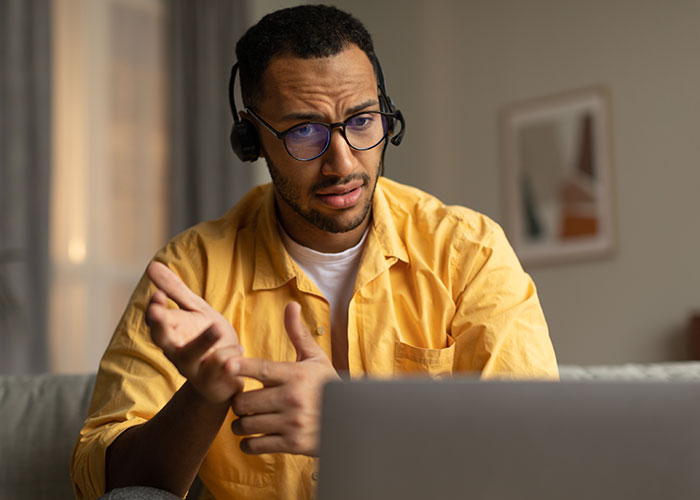 Man wearing headset and glasses, worried about exposing management and HR to coworkers during video call. Man wearing headset and glasses, worried about exposing management and HR to coworkers during video call.
