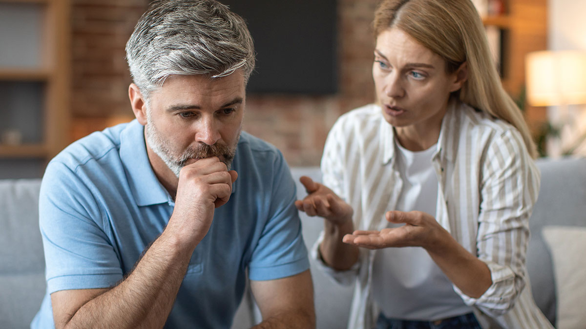 Man refusing to be step-father looks thoughtful while woman explains her feelings in a home setting.