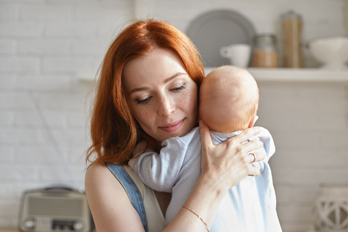 Mother comforting baby indoors, highlighting family emotions while manchild plays games ignoring son's distress. Mother comforting baby indoors, highlighting family emotions while manchild plays games ignoring son's distress.
