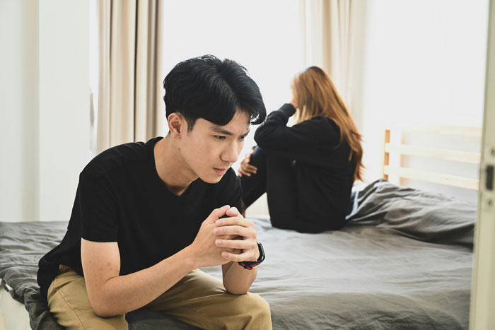 Young couple sitting apart in a bedroom looking upset, illustrating relationship break every year struggles and emotional distance. Young couple sitting apart in a bedroom looking upset, illustrating relationship break every year struggles and emotional distance.