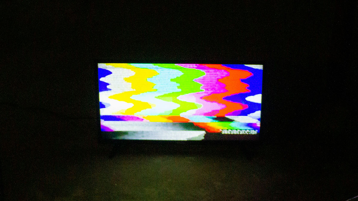 Flickering old TV screen with distorted color bars resembling static in a dark room, evoking scary ghost stories hospital work.