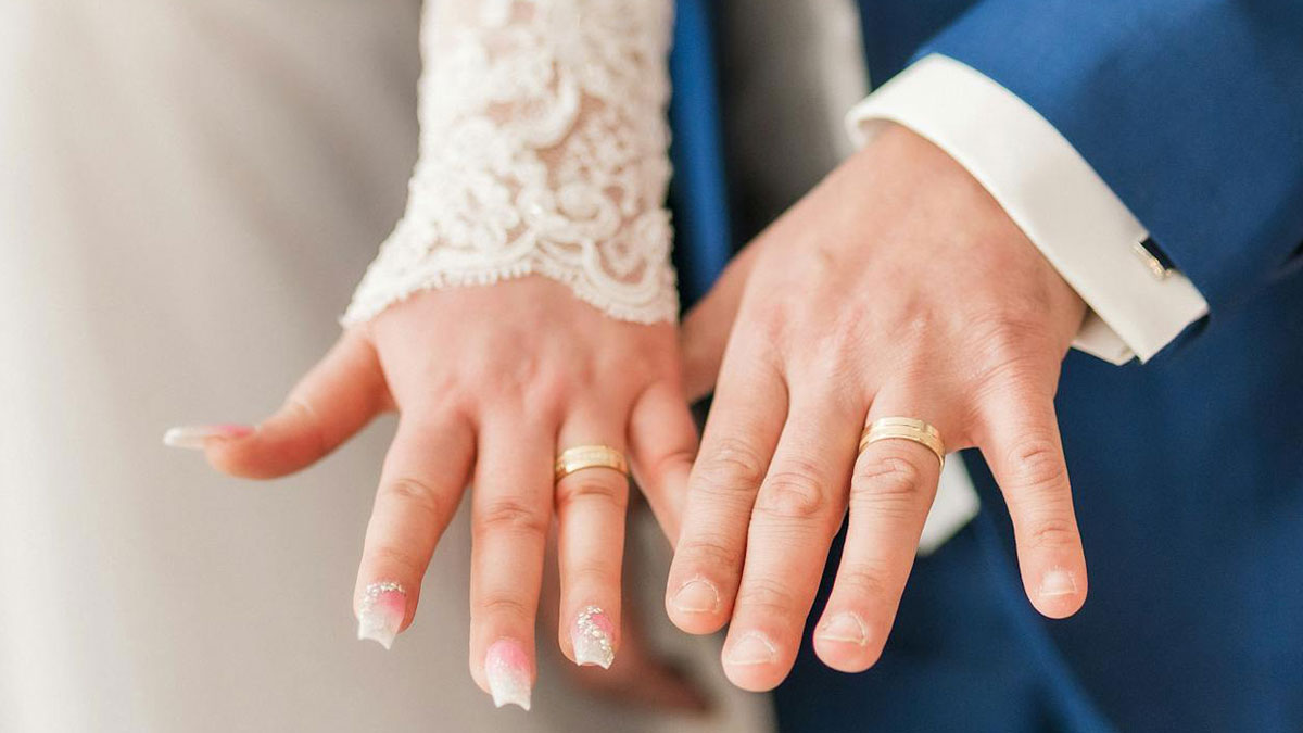 Close-up of married couple showing wedding rings, representing secrets people are hiding from their partners.