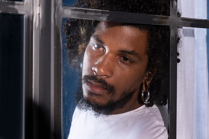 Young man with tear rolling down his cheek, looking out a window, reflecting on learning fiancée is in love with her friend. Young man with tear rolling down his cheek, looking out a window, reflecting on learning fiancée is in love with her friend.