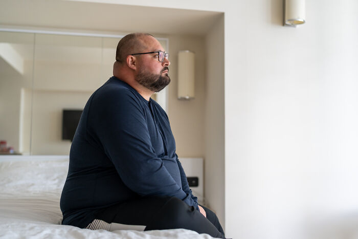 Man sitting on bed looking thoughtful and concerned, representing worst first opinions doctors have heard from patients.