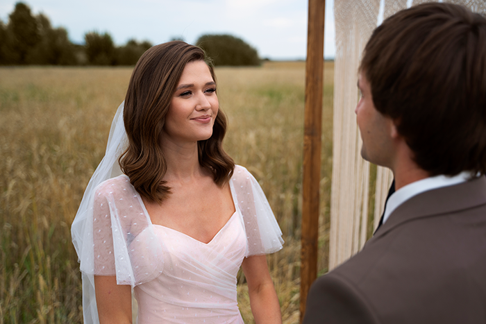 Bride in a white dress with veil standing outdoors facing groom, evoking stepdaughters disown stepmother drama theme. Bride in a white dress with veil standing outdoors facing groom, evoking stepdaughters disown stepmother drama theme.