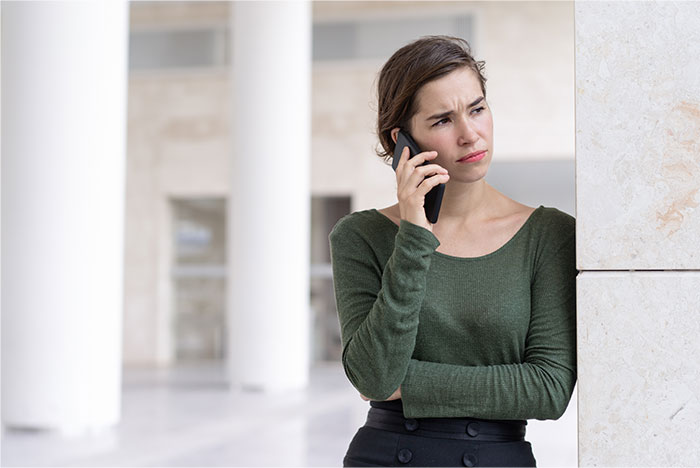 Woman with concerned expression talking on phone, standing indoors, representing sister abandoning autistic brother. Woman with concerned expression talking on phone, standing indoors, representing sister abandoning autistic brother.