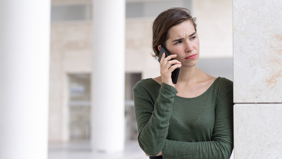 Woman in green top making a concerned phone call, reflecting on her autistic brother and sister abandoning him.