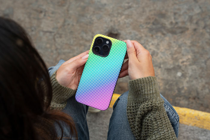 Person holding a colorful phone case, highlighting parents gifting older sibling a phone case versus a $25K car to 17YO child.
