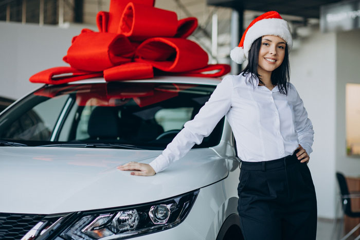 Teen girl in Santa hat leaning on white car with large red bow, representing golden child parents gift $25K car story