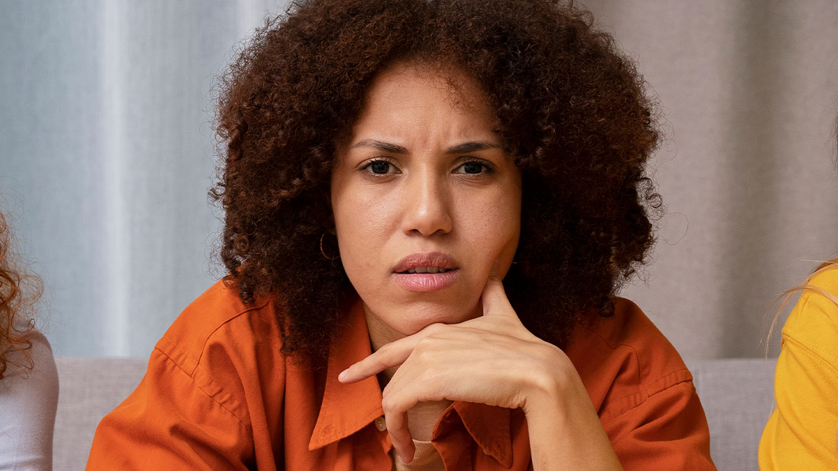 Woman with curly hair looking concerned and upset, reflecting on a long-hidden twin brother story exposed after years of lies