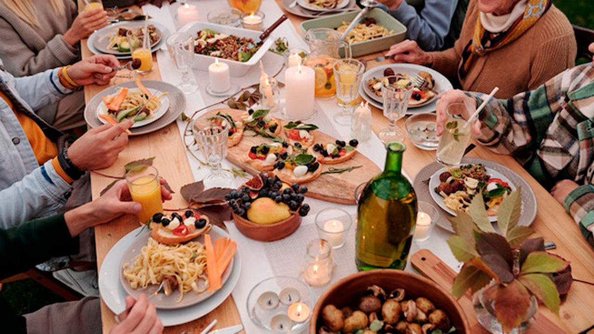 Family dinner gathering with diverse dishes and drinks on table, capturing a moment of silence and reflection.