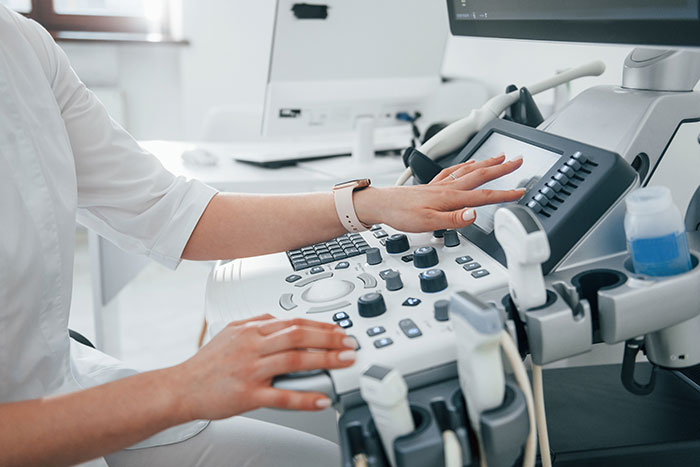 Healthcare professional operating diagnostic ultrasound equipment in hospital setting for medical evaluation and surgery decisions.