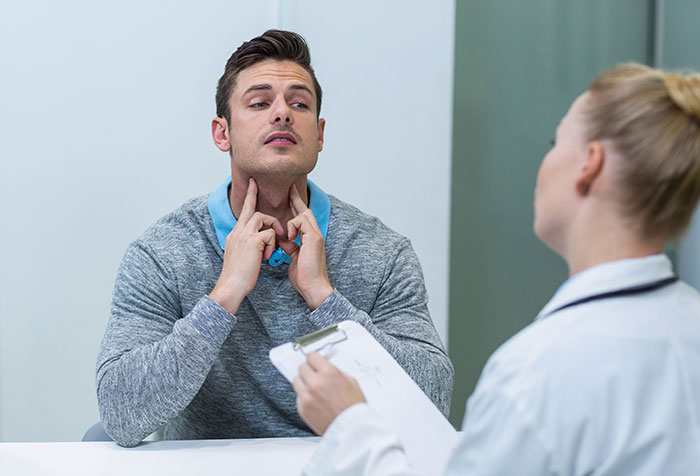 Man pointing to his throat during a medical exam with a doctor, highlighting unexpected hospital surgery cases.