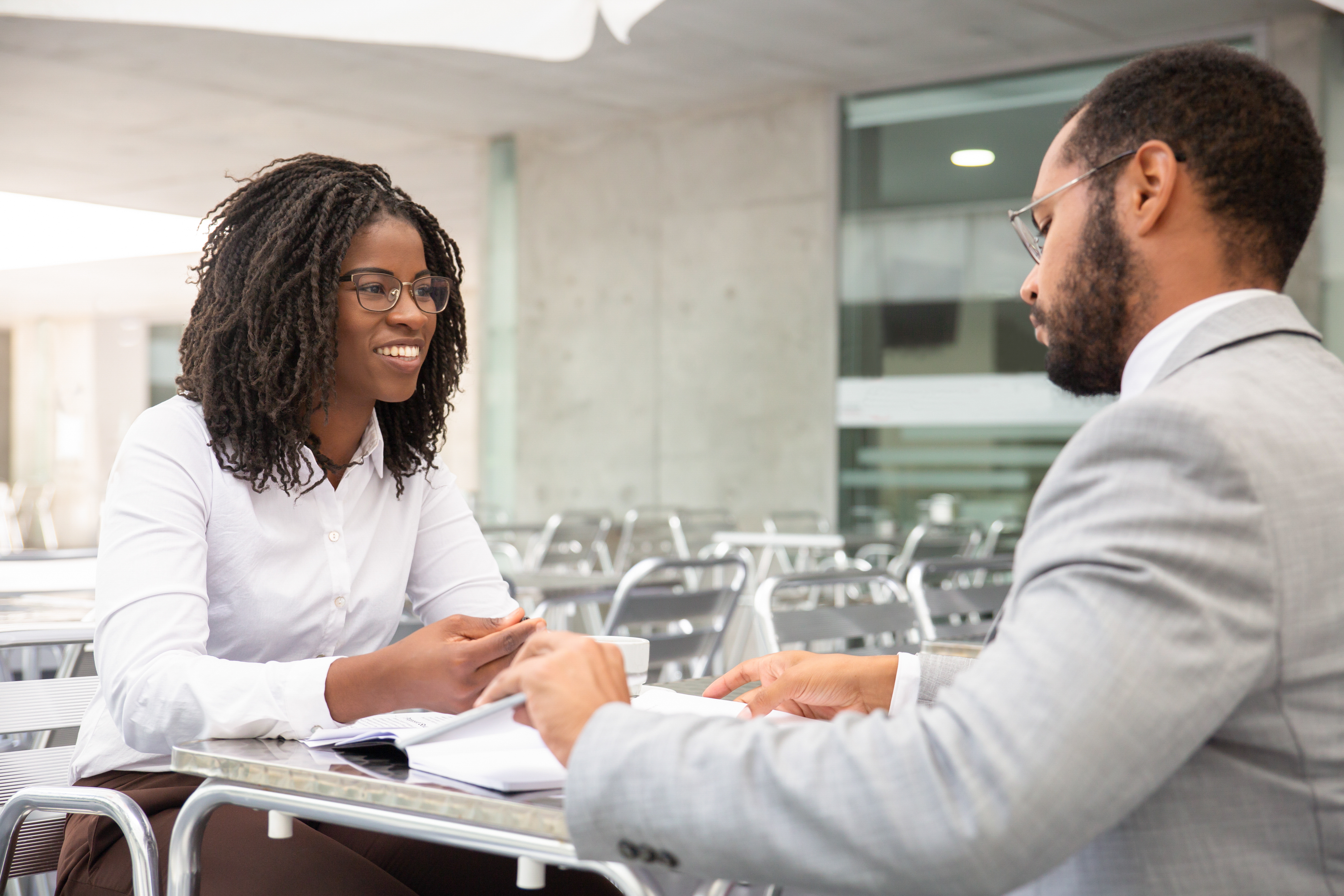 Professional woman in a white shirt interviewing with a man in a gray suit, highlighting job offers after name change. Professional woman in a white shirt interviewing with a man in a gray suit, highlighting job offers after name change.