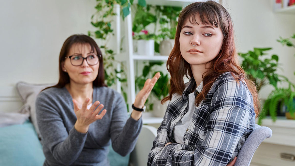 Teen losing patience with golden child cousin during tense family conversation in a cozy living room.
