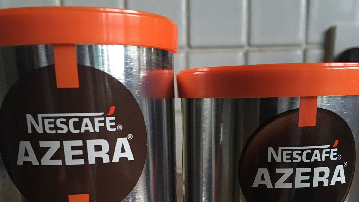 Two Nescafe Azera coffee tins with orange lids illustrating sneakflation in product packaging changes.