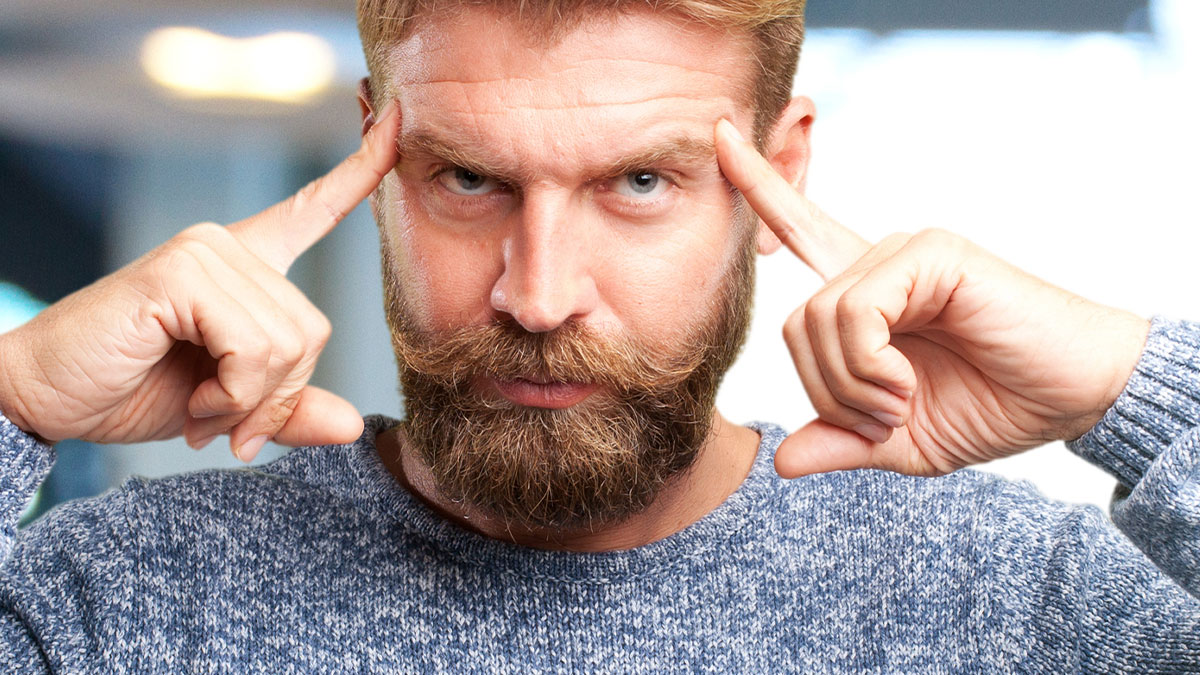 Man with beard and blue sweater concentrating deeply, symbolizing common truths and propaganda misconceptions.