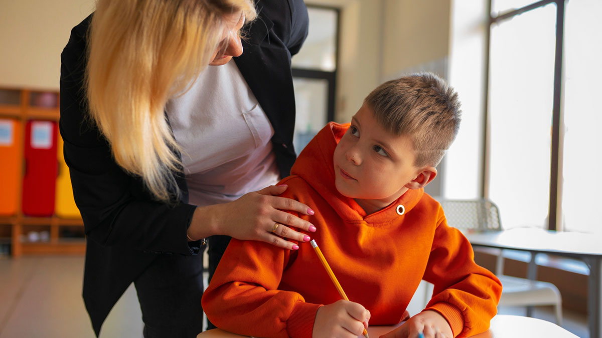 Teacher talks to a young boy in a classroom, highlighting tension around diabetic kid checking glucose at school.