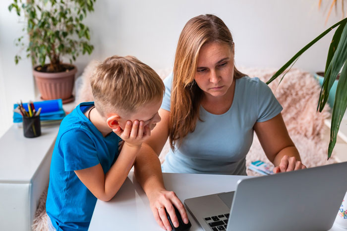 Alt text: Concerned mother and diabetic son looking at laptop discussing glucose check rules set by math teacher at school.