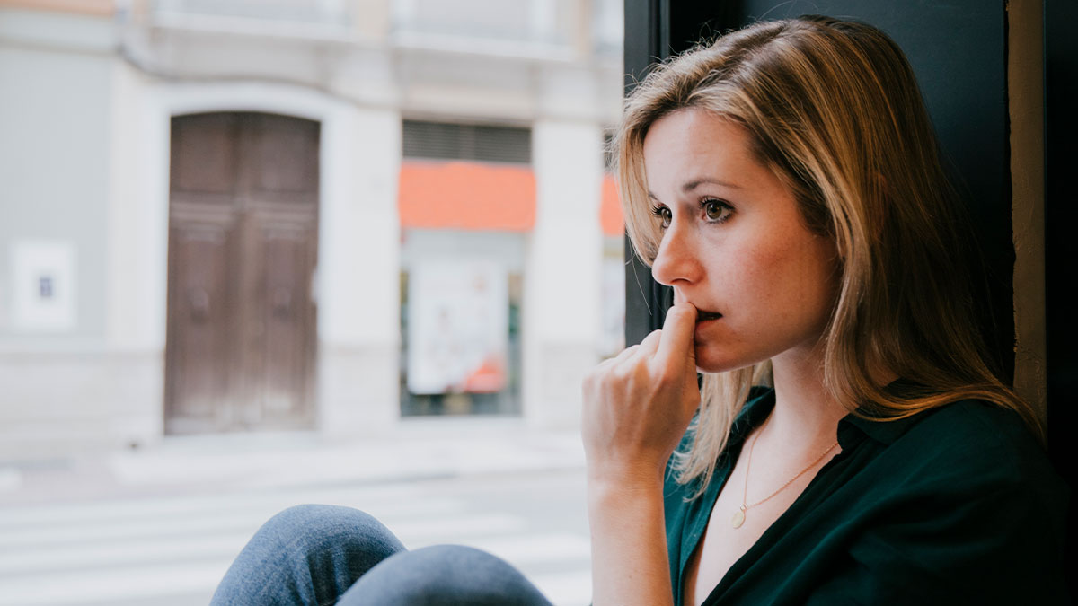 Worried woman sitting by window, reflecting on lesson learned after giving husband another chance.