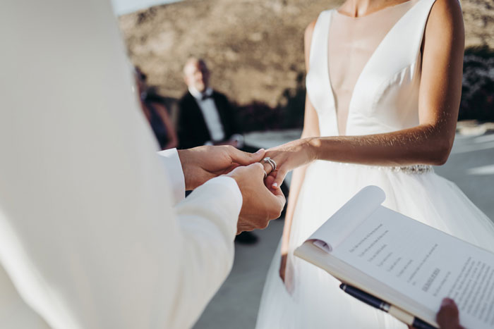 Bride placing ring on groom's finger during outdoor wedding ceremony with Star Wars saga theme inspiration. Bride placing ring on groom's finger during outdoor wedding ceremony with Star Wars saga theme inspiration.