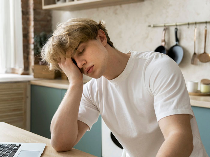 Young man in a white shirt looking stressed at a kitchen table, reflecting on career challenges against dreams. Young man in a white shirt looking stressed at a kitchen table, reflecting on career challenges against dreams.