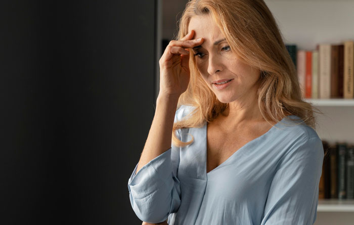 Woman in a blue blouse looking concerned, reflecting on steering her son's career against dreams at home. Woman in a blue blouse looking concerned, reflecting on steering her son's career against dreams at home.