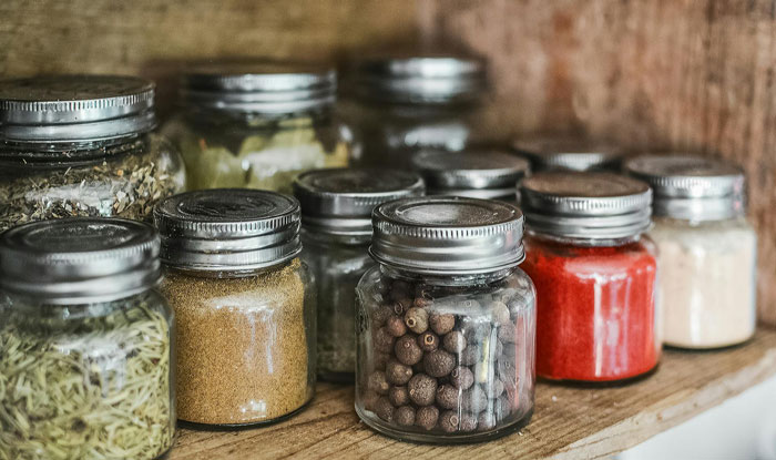 Clear glass jars filled with various spices on a wooden shelf illustrating stepdaughter sister spices drama concept. Clear glass jars filled with various spices on a wooden shelf illustrating stepdaughter sister spices drama concept.