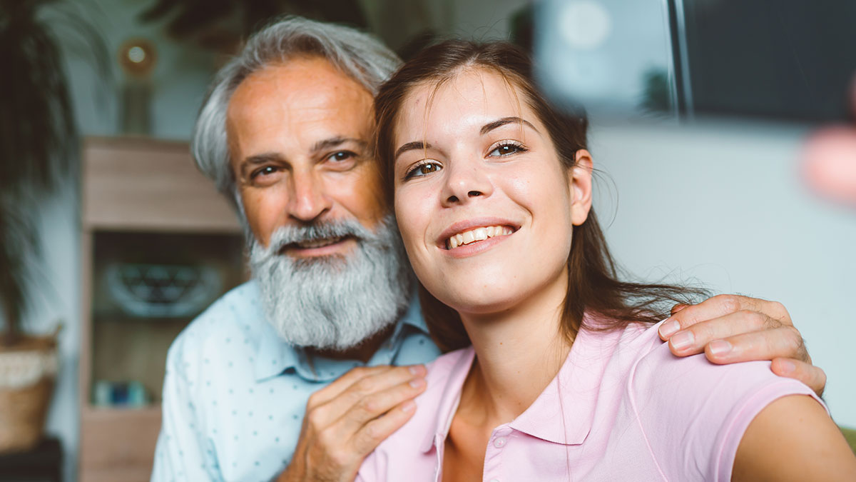 Step-dad and young woman taking a selfie indoors, capturing a moment amid a heartbreaking family situation.