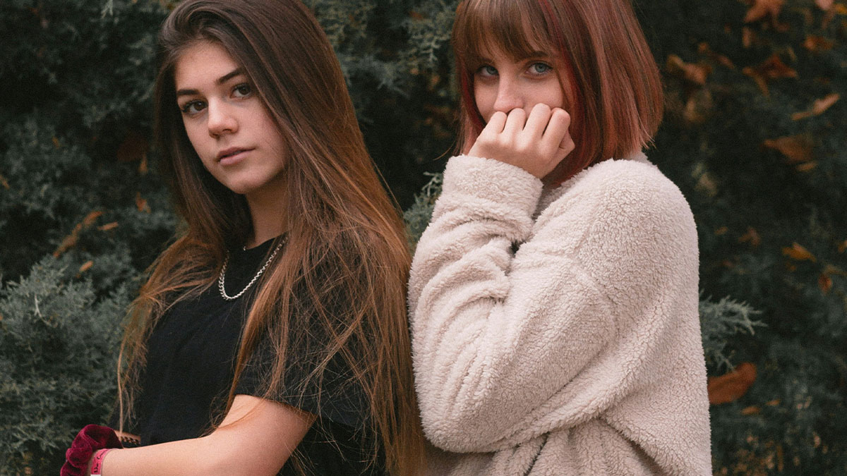 Two teenage girls outdoors showing signs of tension, reflecting stepkids turning cruel when bio mom visits.