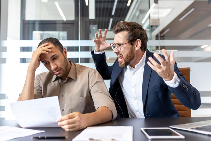 Frustrated boss angrily yelling at stressed worker holding paper, illustrating toxic bosses and hostile work environment. Frustrated boss angrily yelling at stressed worker holding paper, illustrating toxic bosses and hostile work environment.