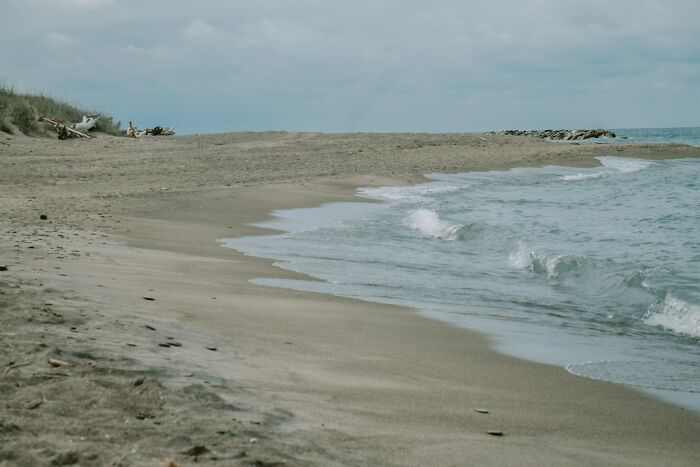 Empty sandy ocean shore with gentle waves under a cloudy sky, showing a calm and fascinating ocean scene. Empty sandy ocean shore with gentle waves under a cloudy sky, showing a calm and fascinating ocean scene.