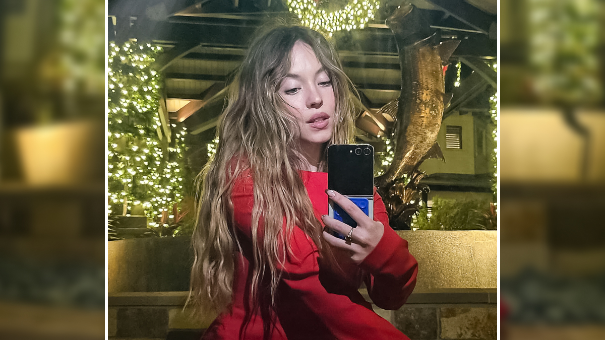 Sydney Sweeney taking a selfie at night with decorative lights, highlighting celebrity privacy rights concerns.
