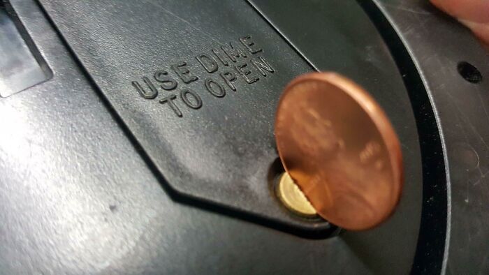 Close-up of a penny inserted exactly as instructed into a slot labeled use dime to open, unhinged pics concept.