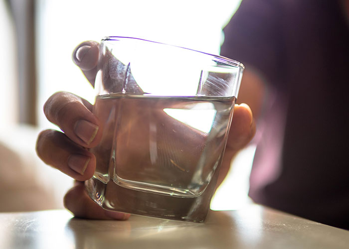Close-up of a woman’s hand holding a glass of water, symbolizing empathy and a tense moment with her boyfriend.