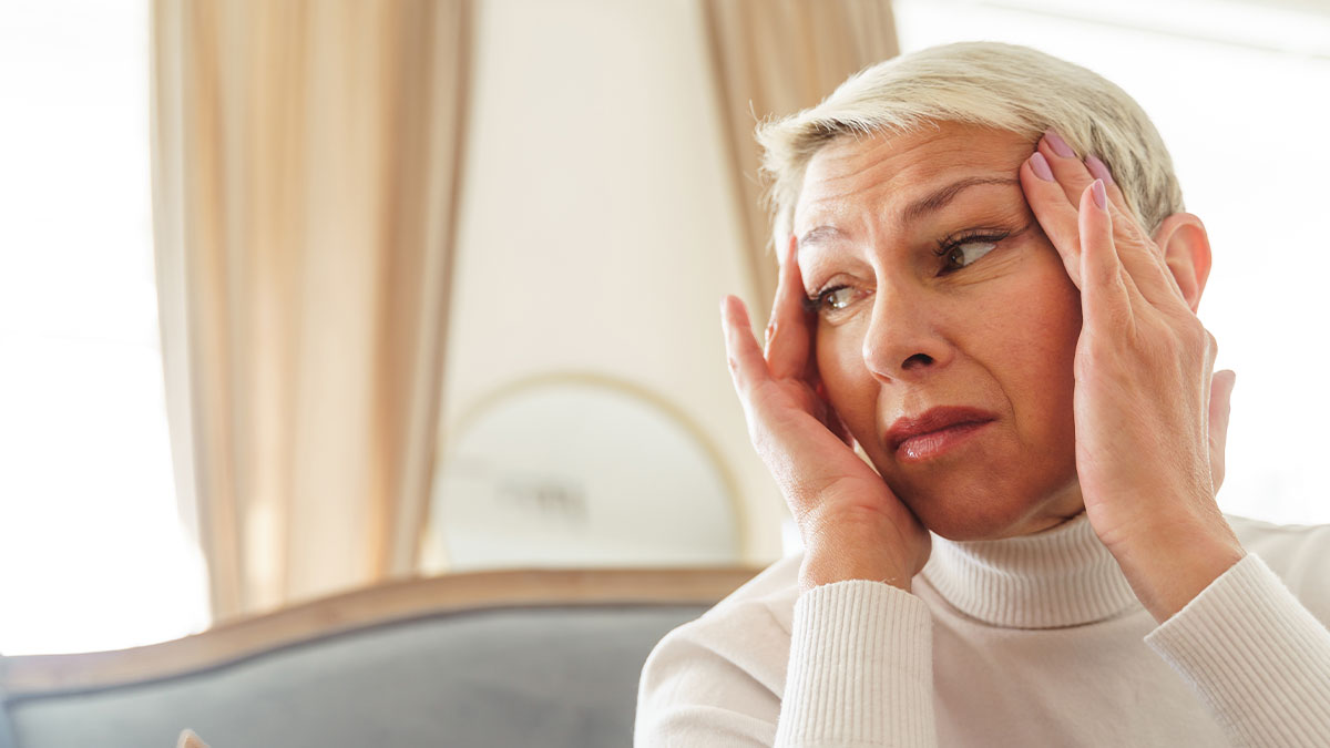 Woman in white sweater holding her head, showing frustration and stress related to stepmom hypocrisy and online lies.