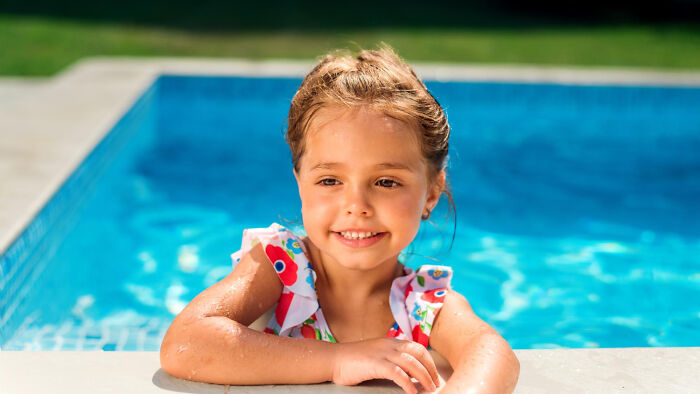 Young girl smiling while resting on the edge of a pool, capturing a moment for tired mom and let down dad. Young girl smiling while resting on the edge of a pool, capturing a moment for tired mom and let down dad.