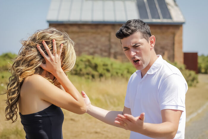 Woman looking tired and frustrated while a man gestures angrily outdoors, depicting a tired mom and let down useless dad. Woman looking tired and frustrated while a man gestures angrily outdoors, depicting a tired mom and let down useless dad.