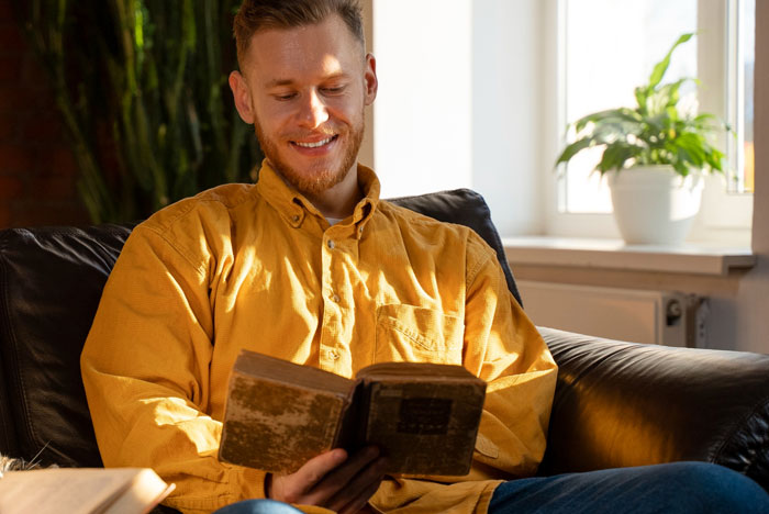 Man in yellow shirt reading a book indoors, illustrating a religious man pushing beliefs on coworkers at work. Man in yellow shirt reading a book indoors, illustrating a religious man pushing beliefs on coworkers at work.
